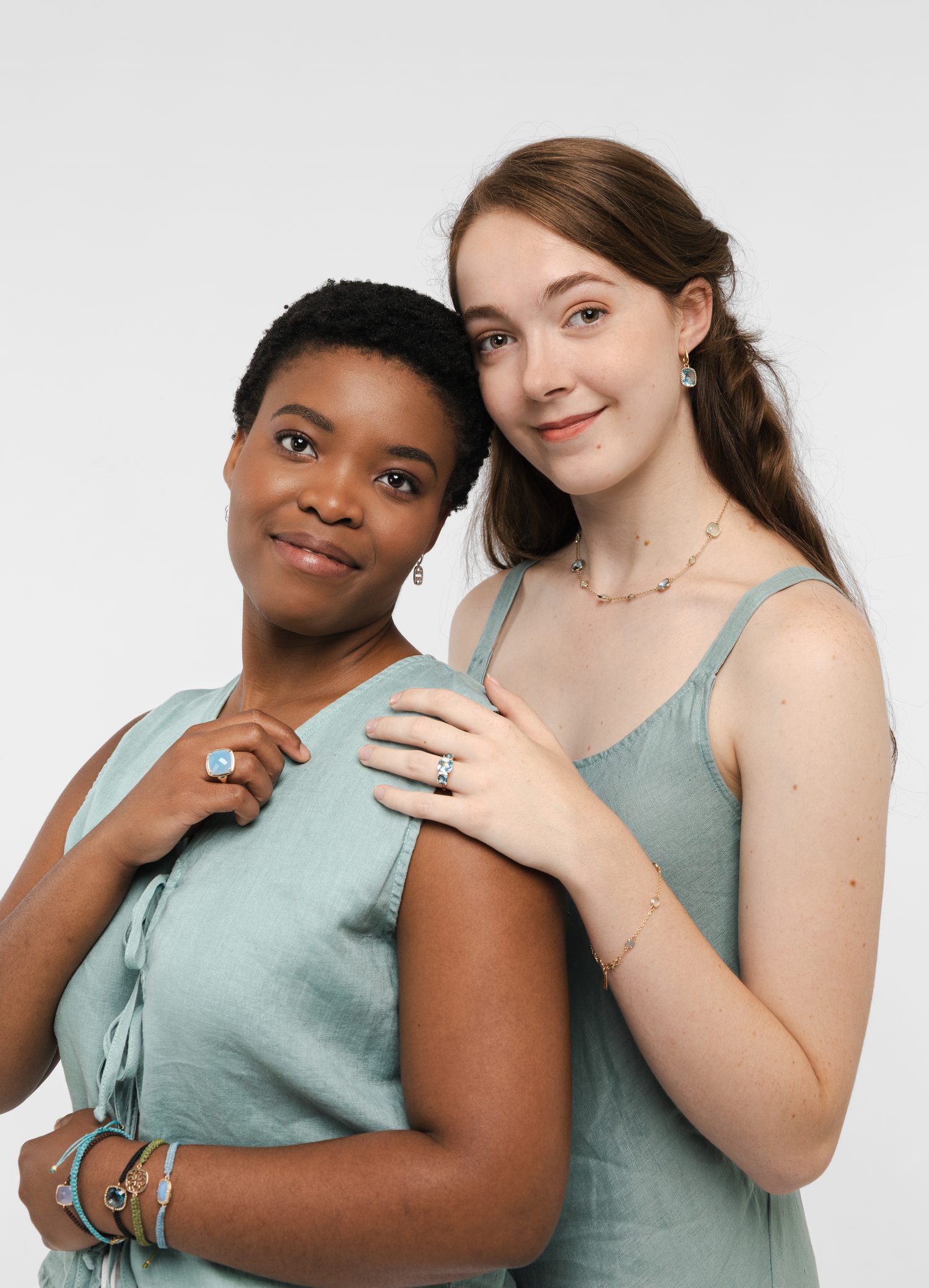 Two women wearing stacked bracelets, rings and fine chains