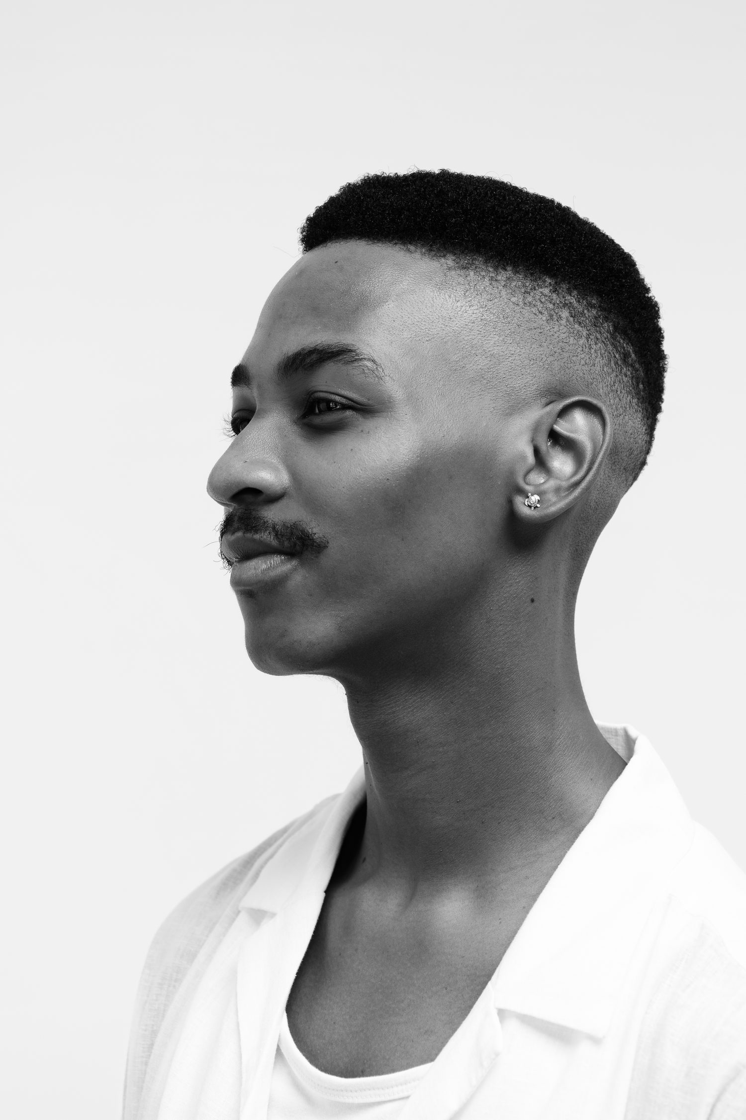 A man in profile wearing a single stud earring